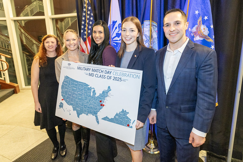 five people standing behind a map posing for a pic.