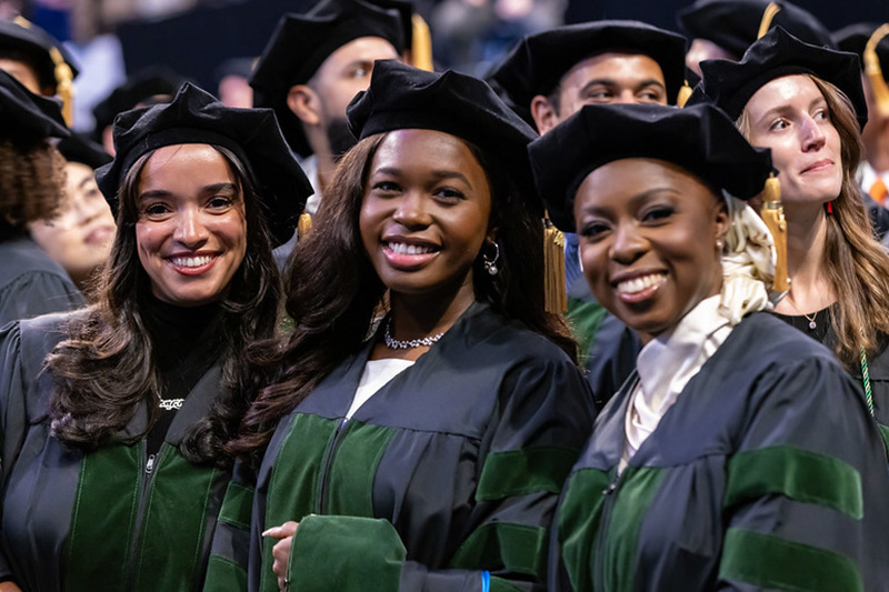 Graduating medical students smile during a Commencement ceremony