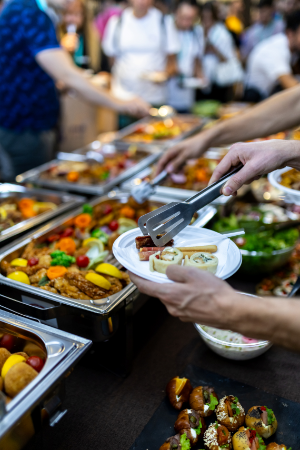 Hands loading a plate with international food