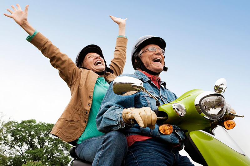 Two older people are riding a lime green motorized scooter and having the time of their life.