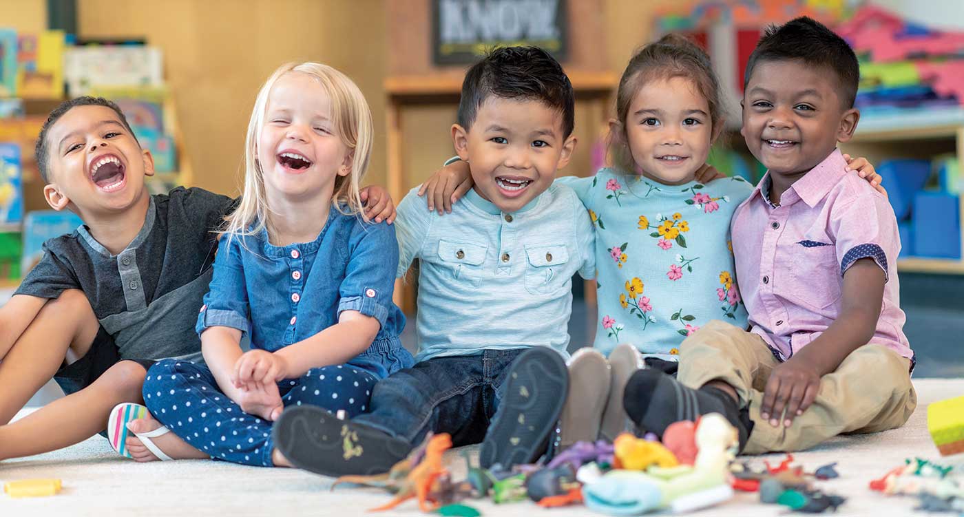 Toddlers in a classroom laughing and smiling