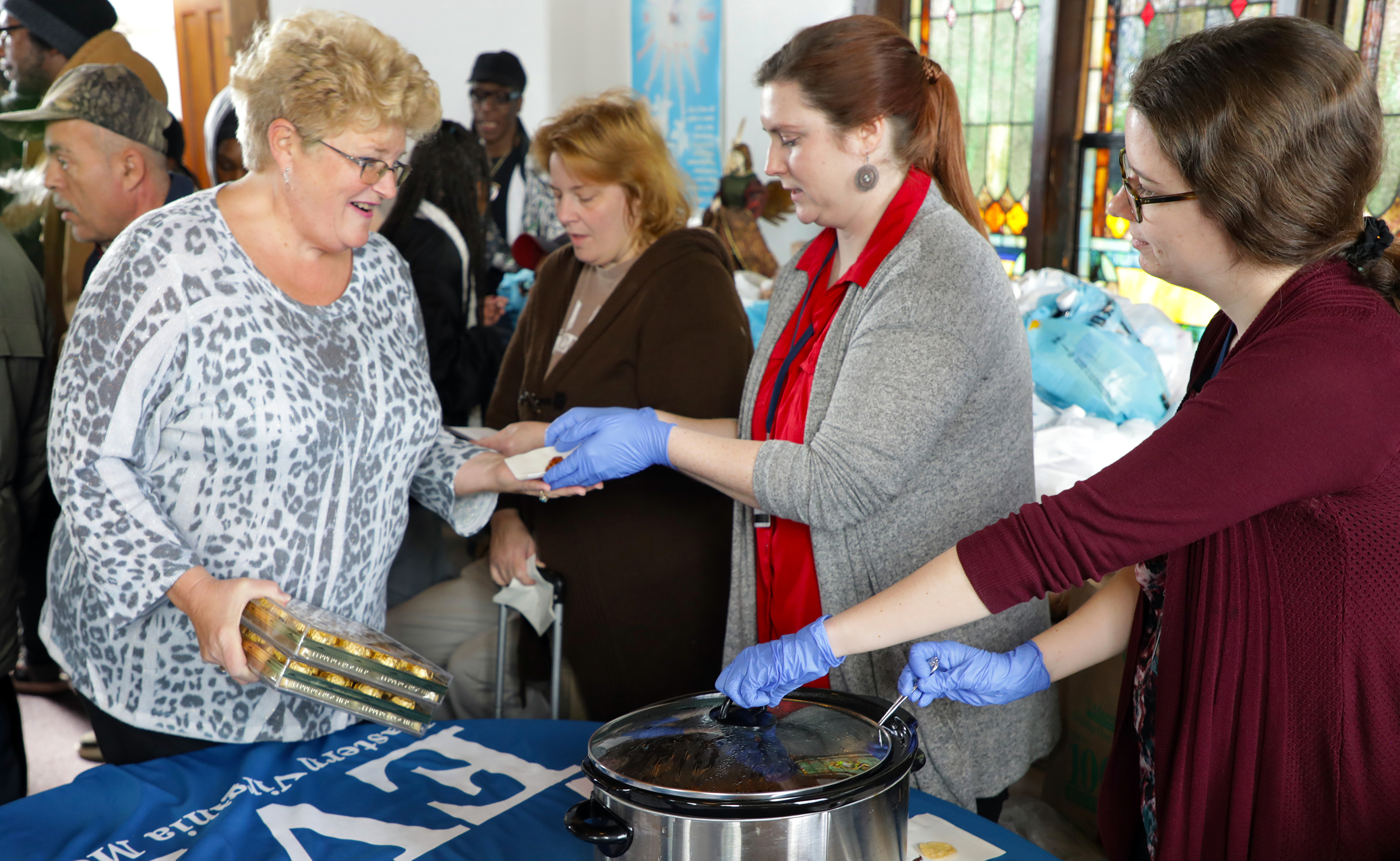 During a recent food-pantry distribution at Port Norfolk Church in Portsmouth, Pastor Connie Shoemaker (left) worked with EVMS staff members
      Bray Nemetz-Gardner and April Reichmeider of the Portsmouth Diabetes Prevention Project.