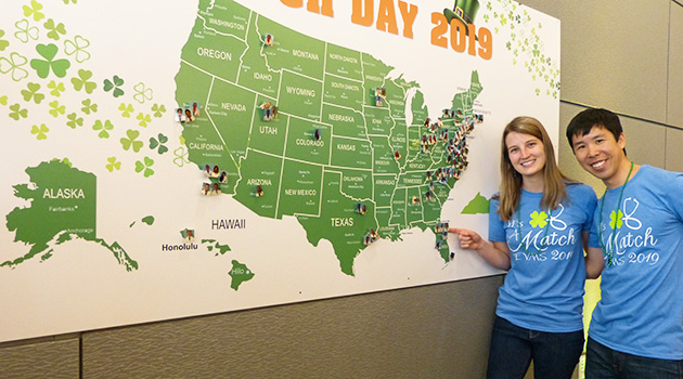Two fourth-year EVMS medical students point to a map of the United States at Match Day 2019